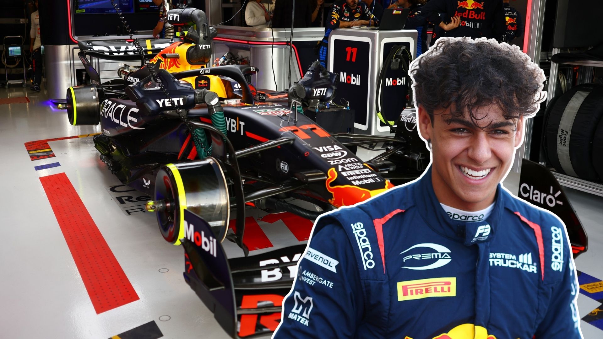En ung förare i Prema Racing-overall med ett stort leende står framför en Red Bull Formel 1-bil i ett F1-garage. Bilen och teamets utrustning syns tydligt i bakgrunden, med logotyper från sponsorer som Oracle och Mobil.