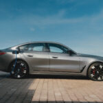 BMW står och laddar med en kvinna gåendes till höger i bild.