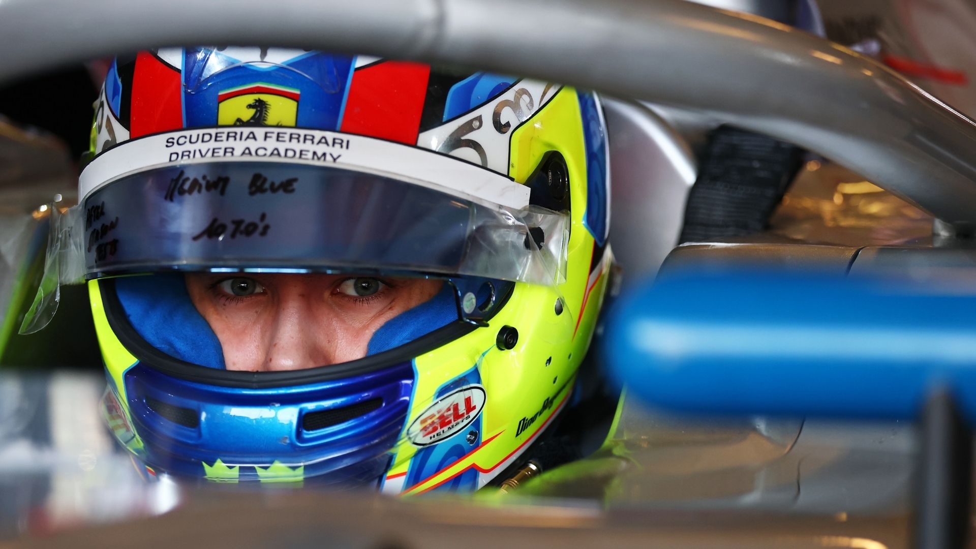 Dino Beganovic i närbild med hjälmen på, som visar Ferrari Driver Academy-loggan. Förbereder sig inför en viktig säsong i Formel 2.