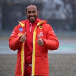 Lewis Hamilton i Ferrari-kläder ger tummen upp under en regnig dag på banan. Den sjufaldige världsmästaren är redo för sin första säsong med Scuderia Ferrari.