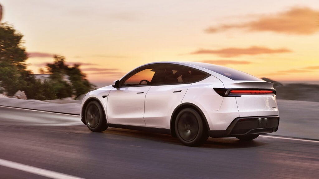 Nya Tesla Model Y kör på väg. Bild tagen snett bakifrån. 