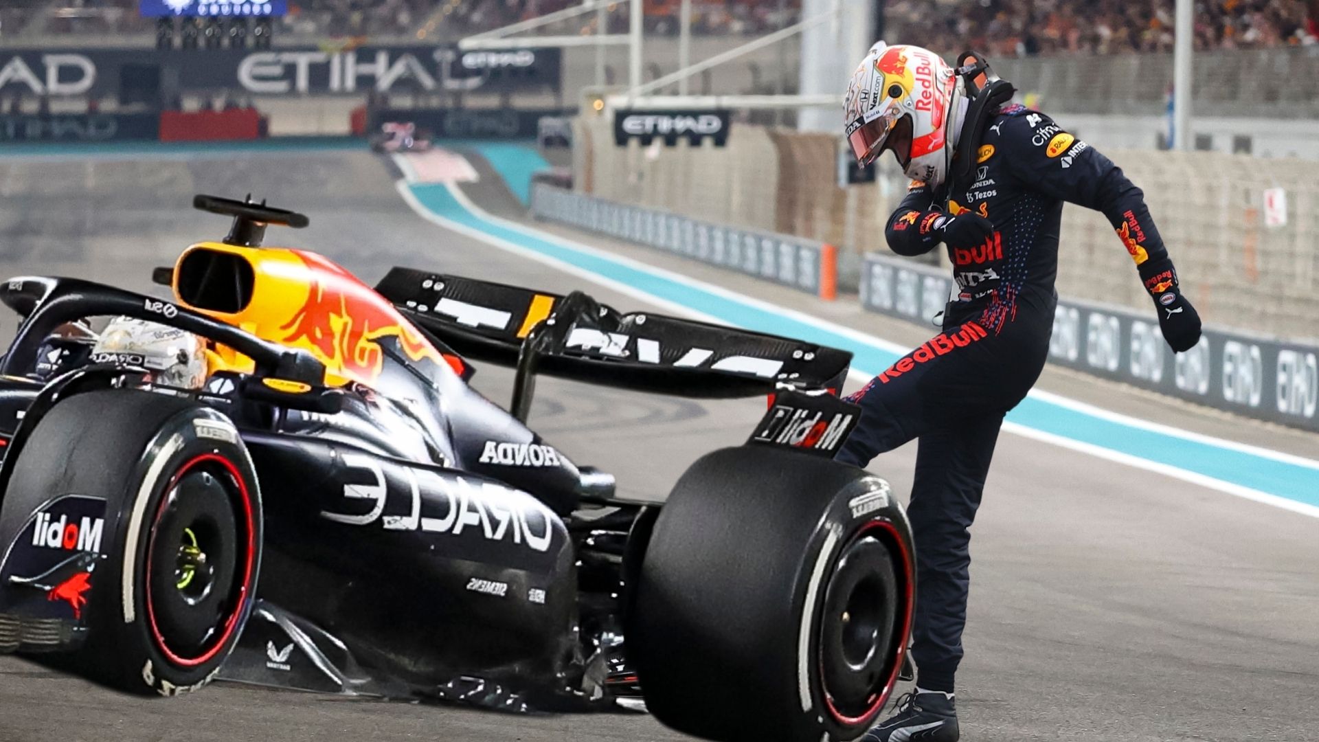 En Red Bull RB20 står stilla på banan med en förare i Red Bulls tävlingsoverall som frustrerat sparkar på bilen efter tekniska problem under ett lopp.