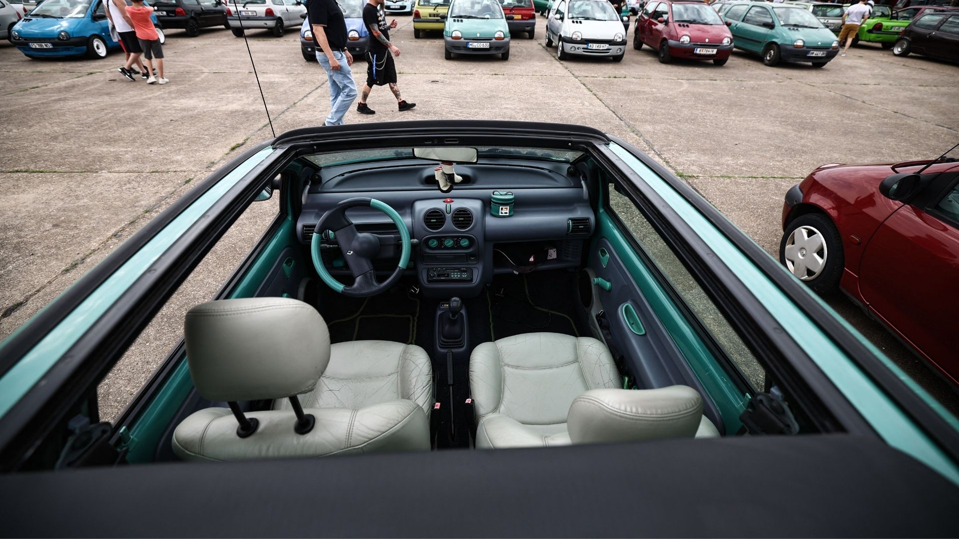 Interiör av en första generationens Renault Twingo med unika färgdetaljer och en öppen taklösning på en bilträff.